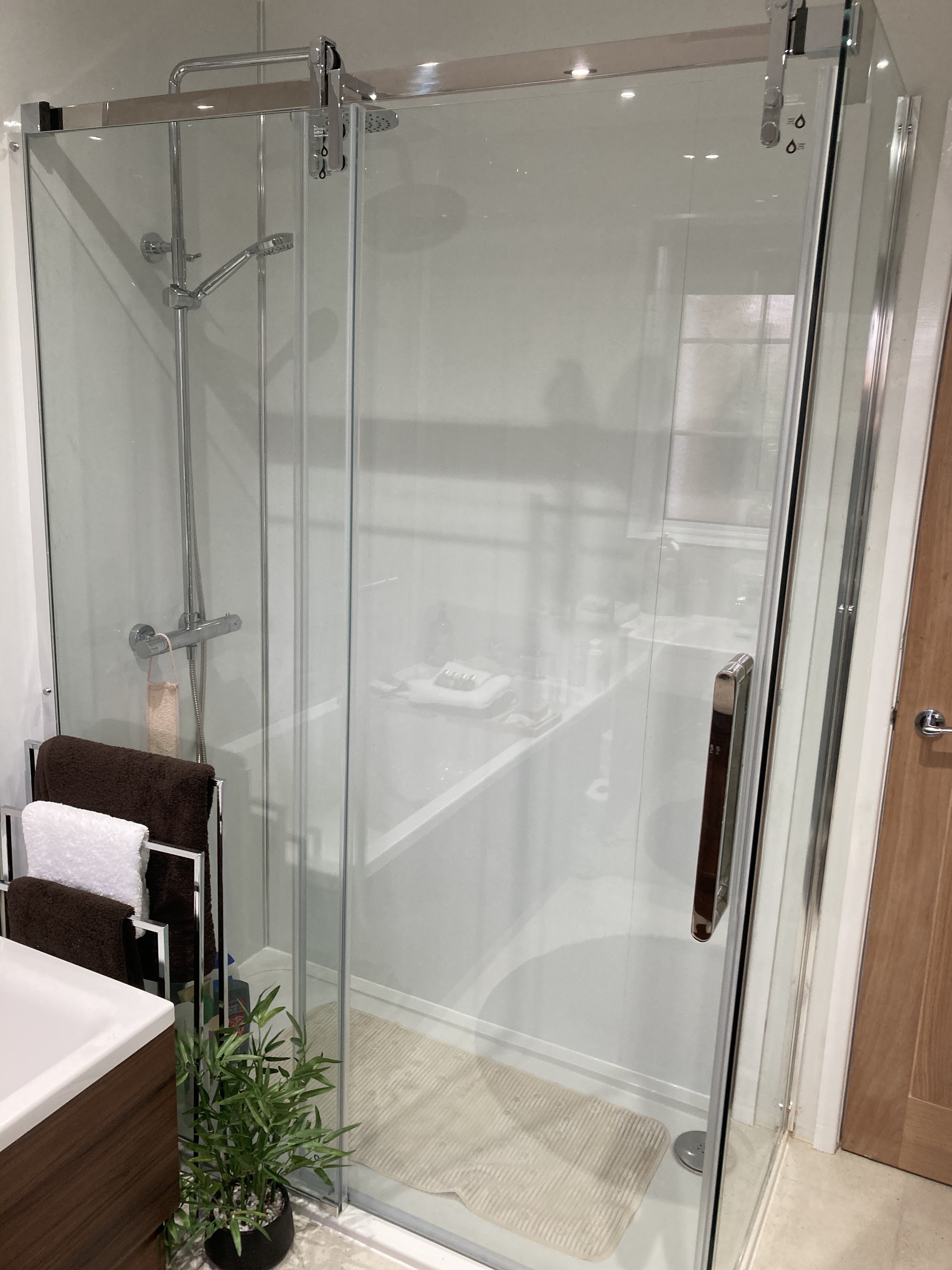 A finished bathroom with a large glass shower enclosure and chrome fittings
