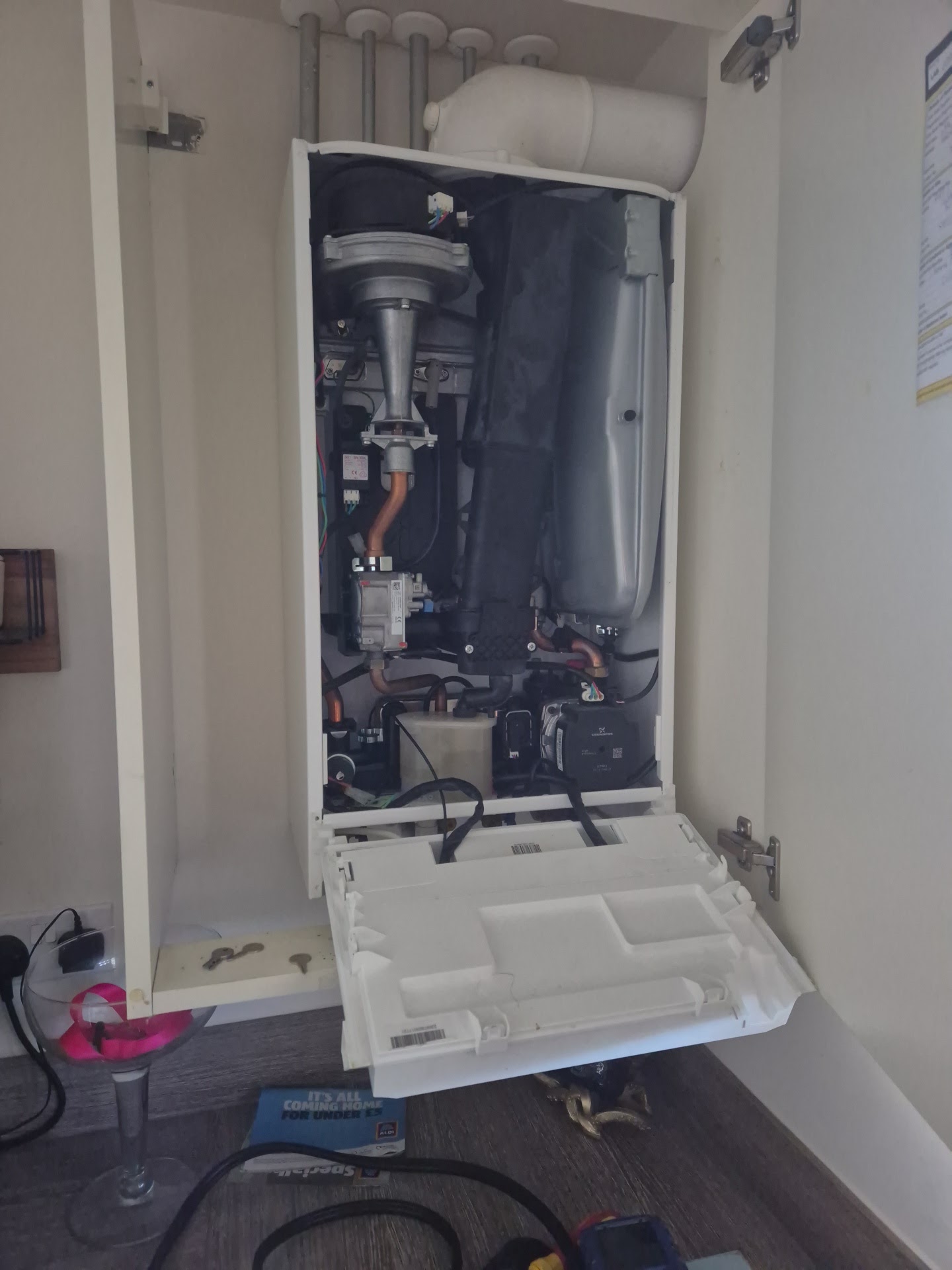 A boiler opened up inside a kitchen cupboard during a service